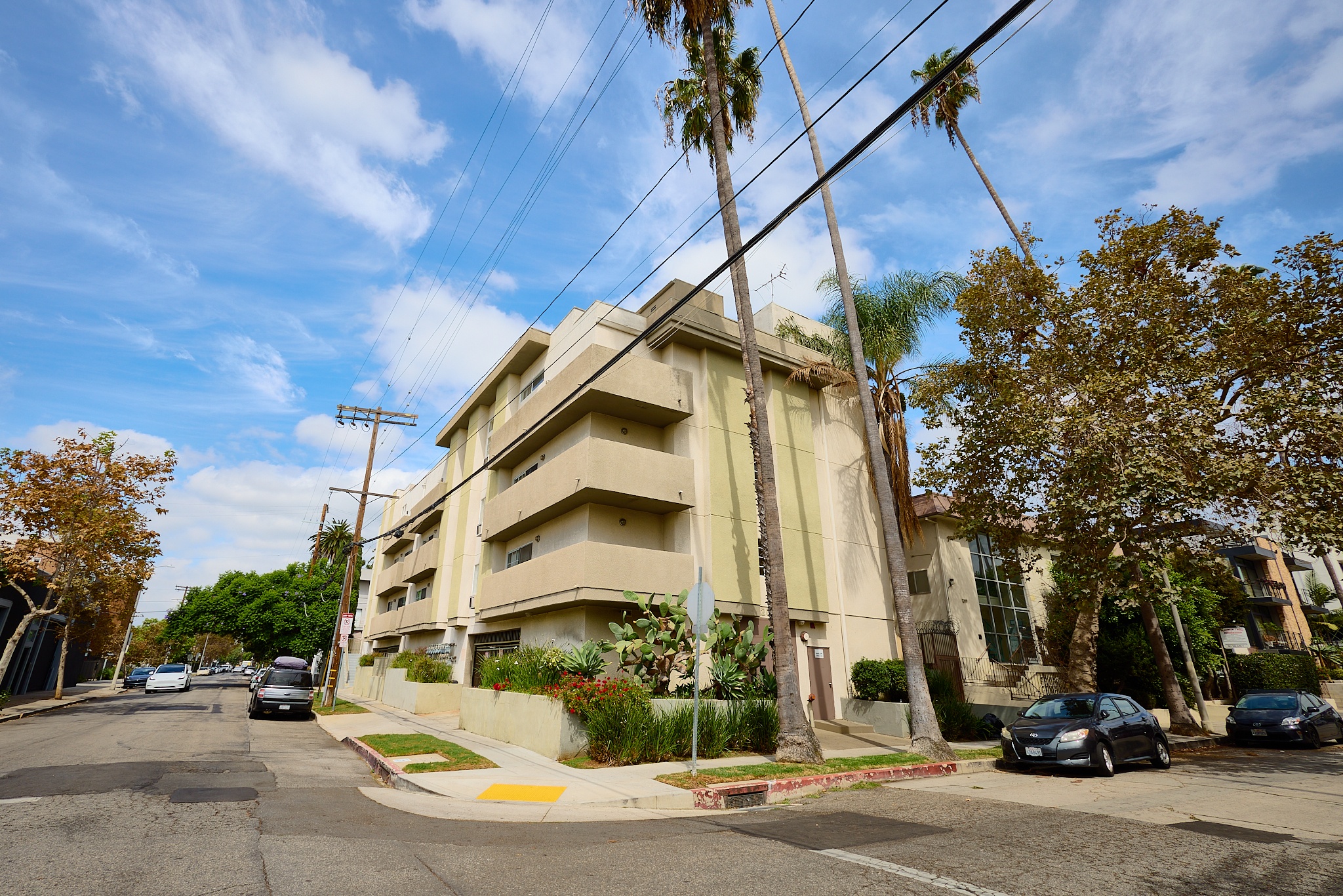 A street view of a residential area with cars parked on the side of the road.